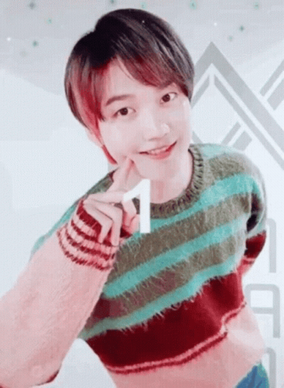 A Young Man Wearing A Striped Sweater Is Making A Heart Shape With His Hand . GIF