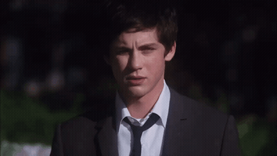 A Young Man Wearing A Suit And Tie Looks At The Camera GIF