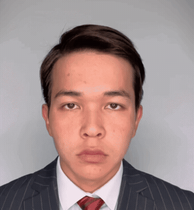 A Young Man Wearing A Suit And Tie Looks At The Camera GIF
