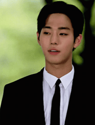 A Young Man Wearing A Suit And Tie Looks To His Left GIF