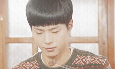 A Young Man Wearing A Sweater Is Eating A Piece Of Food GIF