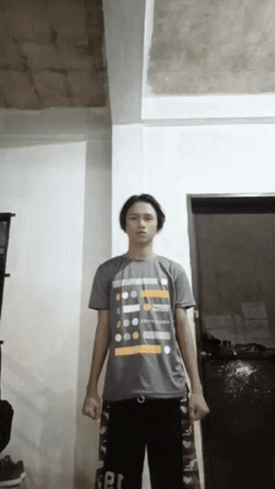 A Young Man Wearing A T-Shirt That Says ' Happiness ' On It Stands In A Room GIF