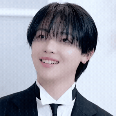 A Young Man Wearing A Tuxedo And Tie Is Smiling GIF