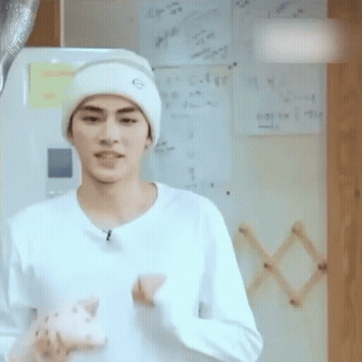 A Young Man Wearing A White Hat And A White Shirt Is Holding A Stuffed Animal . GIF