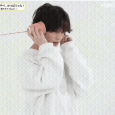 A Young Man Wearing A White Hoodie Is Talking On A Cell Phone . GIF