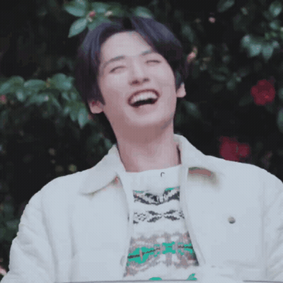A Young Man Wearing A White Jacket And A Sweater Is Laughing With His Eyes Closed . GIF