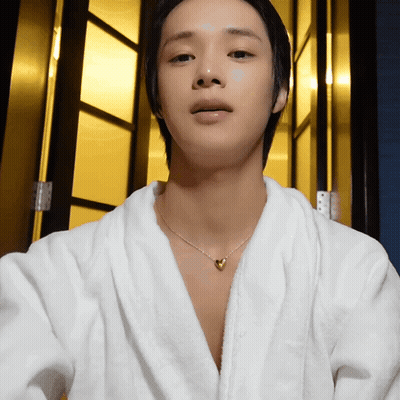 A Young Man Wearing A White Robe And A Heart Necklace GIF