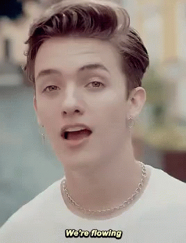 A Young Man Wearing A White Shirt And A Chain Necklace Says We 'Re Flowing GIF
