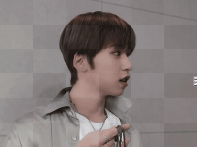 A Young Man Wearing A White Shirt And A Necklace Looks To The Side GIF