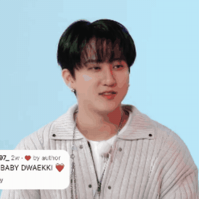 A Young Man Wearing A White Sweater And A Necklace Has A Sticker On His Neck That Says Baby Dwaekki GIF