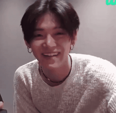 A Young Man Wearing A White Sweater Is Smiling GIF