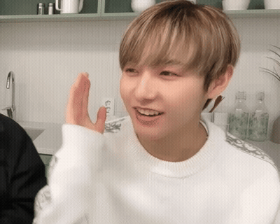 A Young Man Wearing A White Sweater Is Waving His Hand GIF