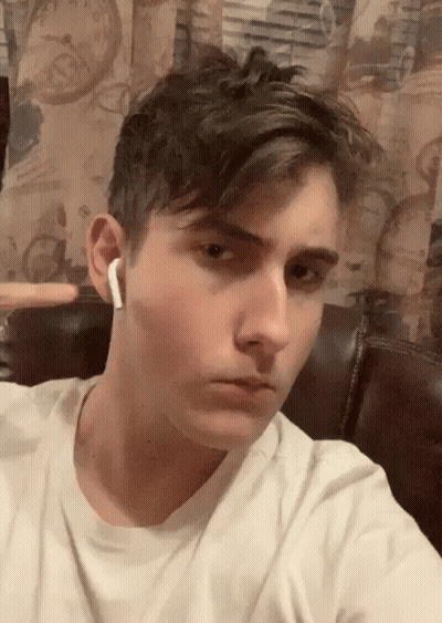 A Young Man Wearing A White T-Shirt And White Earbuds Takes A Selfie GIF