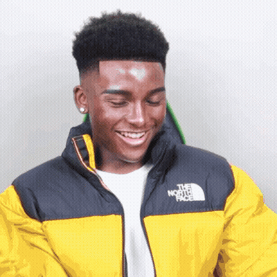 A Young Man Wearing A Yellow North Face Jacket Smiles GIF