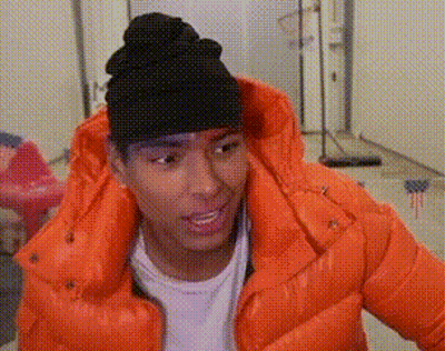 A Young Man Wearing An Orange Jacket And A Black Beanie . GIF