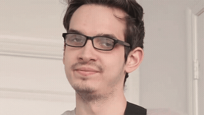 A Young Man Wearing Glasses And A Beard Looks At The Camera GIF