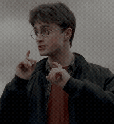 A Young Man Wearing Glasses And A Black Jacket Is Pointing His Finger Up . GIF