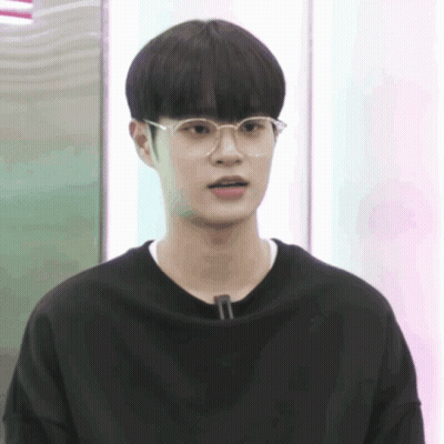 A Young Man Wearing Glasses And A Black Shirt Is Looking At The Camera GIF