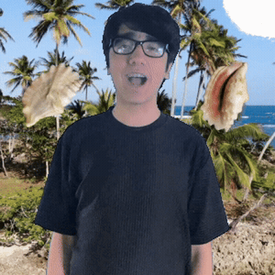 A Young Man Wearing Glasses And A Black Shirt Is Standing In Front Of Palm Trees And The Ocean GIF