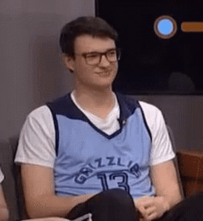 A Young Man Wearing Glasses And A Blue Grizzlies Jersey Is Sitting In A Chair . GIF