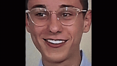 A Young Man Wearing Glasses And A Blue Shirt Is Smiling . GIF