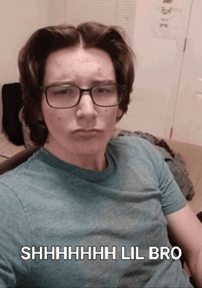 A Young Man Wearing Glasses And A Blue Shirt Says Shhhh Lil Bro On The Bottom GIF