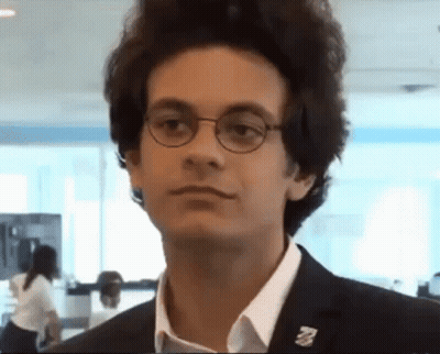 A Young Man Wearing Glasses And A Pin That Says ' A ' On It GIF