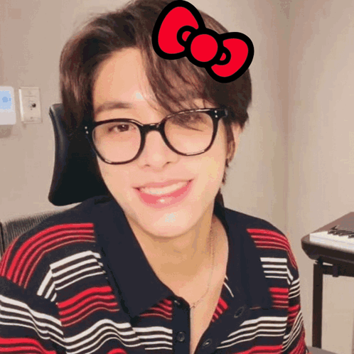 A Young Man Wearing Glasses And A Red Bow On His Head GIF
