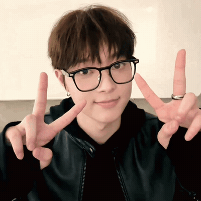 A Young Man Wearing Glasses And A Ring Is Giving The Peace Sign GIF