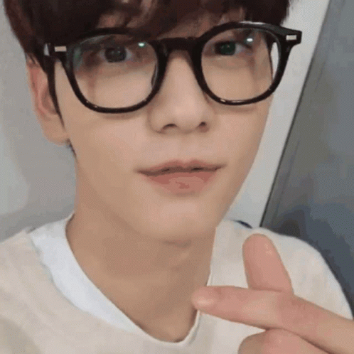 A Young Man Wearing Glasses And A White Shirt Is Making A Peace Sign . GIF