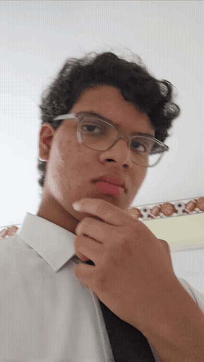 A Young Man Wearing Glasses And A White Shirt Looks At The Camera GIF