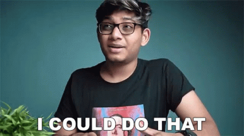 A Young Man Wearing Glasses Is Saying `` I Could Do That '' While Sitting In Front Of A Plant . GIF