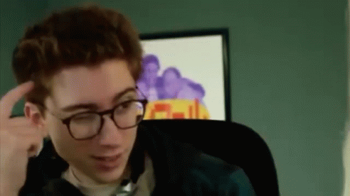 A Young Man Wearing Glasses Is Sitting In A Chair In Front Of A Computer Screen . GIF