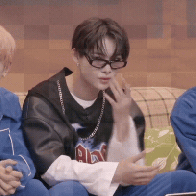 A Young Man Wearing Glasses Is Sitting On A Couch With Other People . GIF