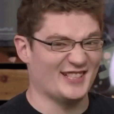 A Young Man Wearing Glasses Is Smiling And Making A Face . GIF