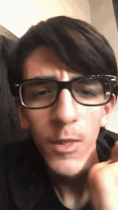 A Young Man Wearing Glasses Looks At The Camera GIF