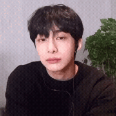 A Young Man Wearing Headphones And A Black Shirt Is Looking At The Camera . GIF