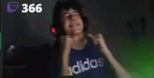 A Young Man Wearing Headphones And A Blue Adidas Shirt Is Dancing In A Dark Room . GIF