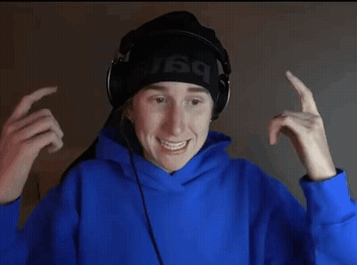 A Young Man Wearing Headphones And A Blue Hoodie Is Making A Face . GIF