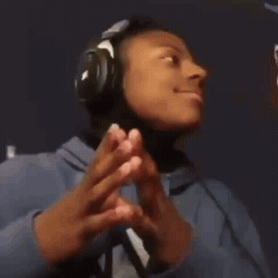 A Young Man Wearing Headphones And A Blue Hoodie Is Making A Peace Sign . GIF