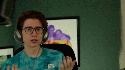 A Young Man Wearing Headphones And A Blue Tie Dye Shirt With A Cat On It GIF