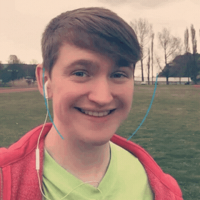 A Young Man Wearing Headphones And A Green Shirt Smiles GIF