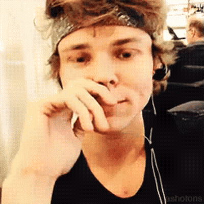 A Young Man Wearing Headphones And A Headband Is Covering His Mouth With His Hand GIF
