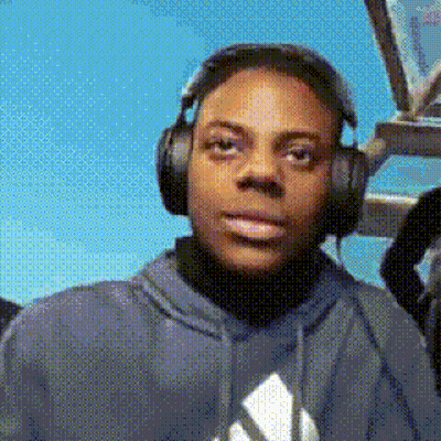 A Young Man Wearing Headphones And A Hoodie Is Looking At The Camera . GIF
