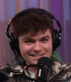 A Young Man Wearing Headphones And A Microphone Is Smiling . GIF