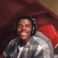 A Young Man Wearing Headphones And A Plaid Shirt Is Smiling GIF