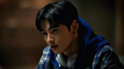 A Young Man Wearing Headphones And A Plaid Shirt Looks Down GIF