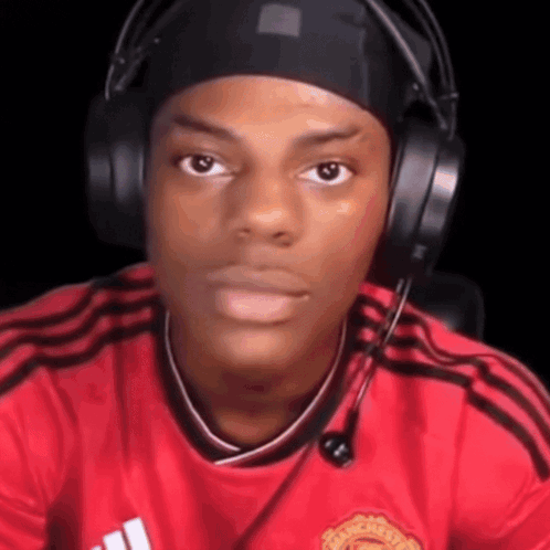 A Young Man Wearing Headphones And A Red Shirt Is Making A Funny Face . GIF