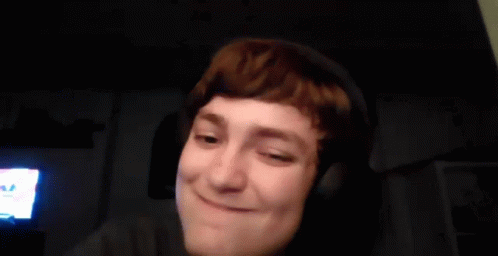 A Young Man Wearing Headphones Is Making A Funny Face In A Dark Room . GIF
