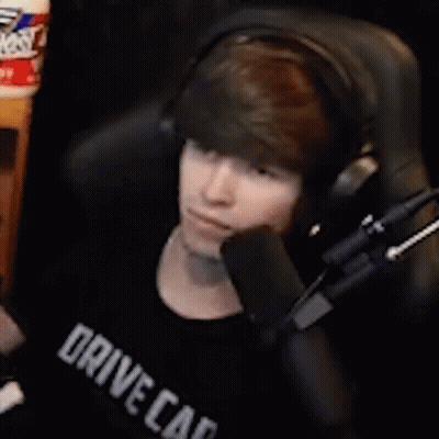 A Young Man Wearing Headphones Is Sitting In Front Of A Microphone And Talking Into It . GIF